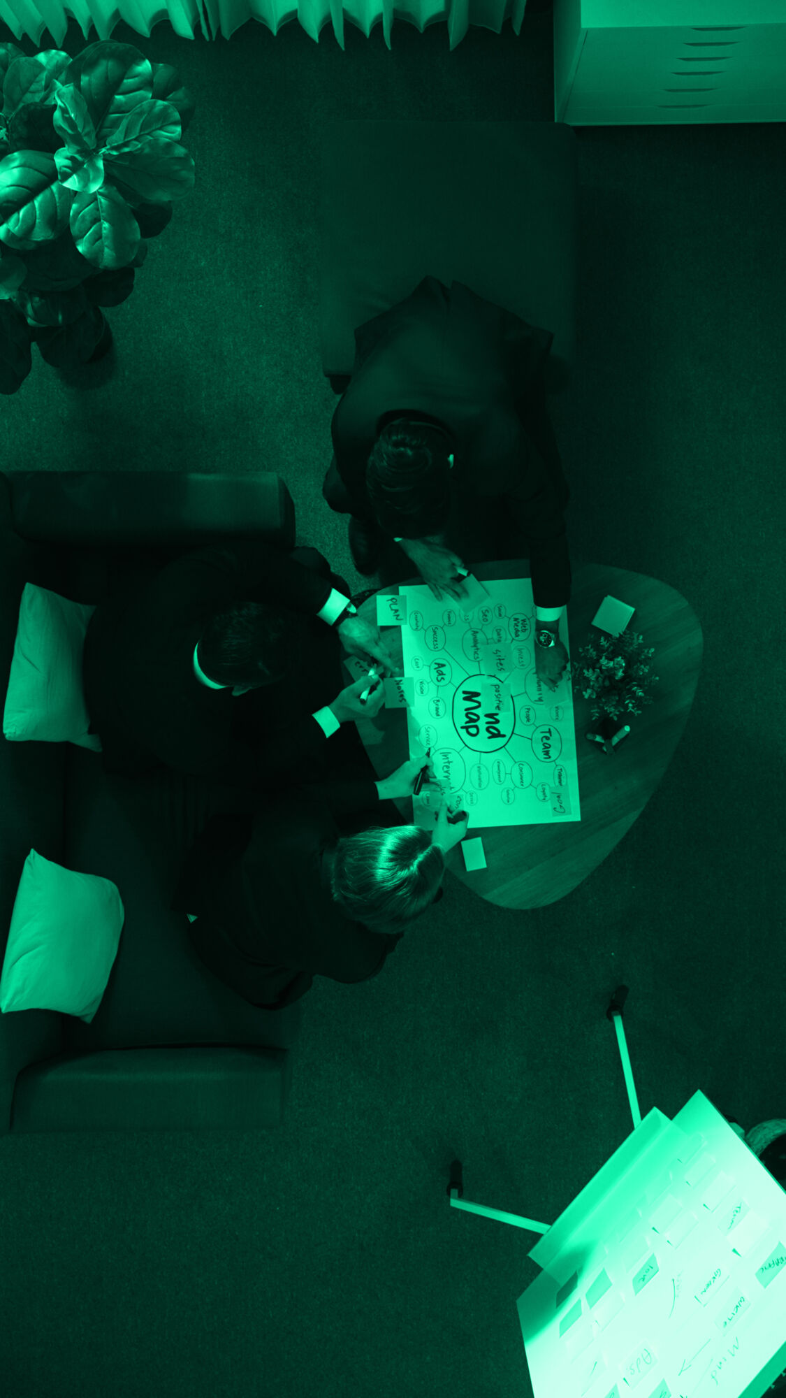 Top view of businesswoman write marketing idea on stick notes while standing near group of diverse people brainstorm financial strategy by using mind map. Start up team working together. Directorate.